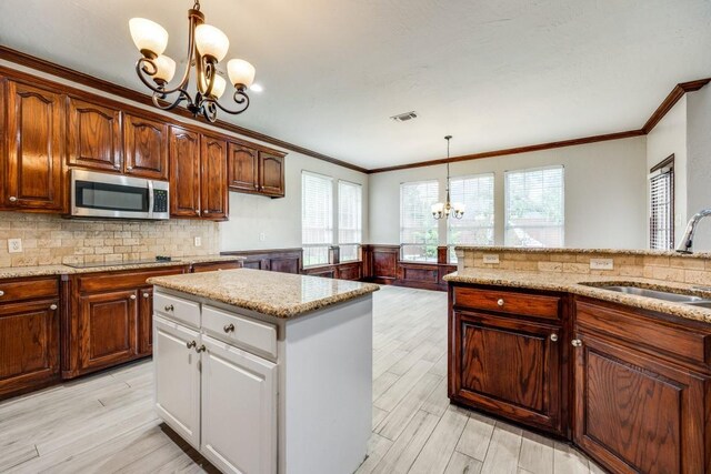 kitchen featuring a chandelier, black electric cooktop, sink, a kitchen island, and pendant lighting