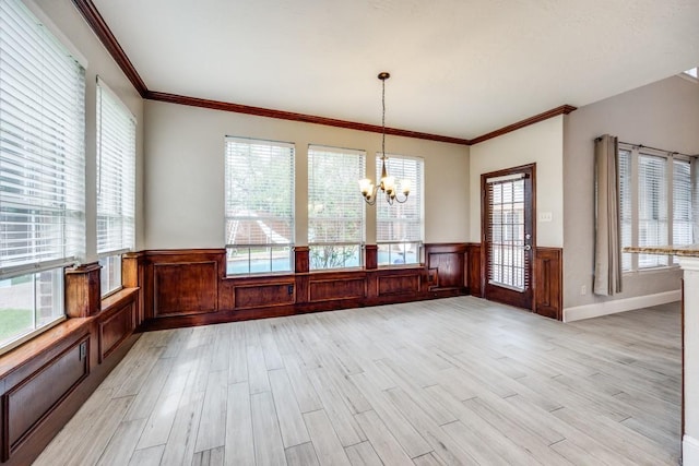 unfurnished dining area featuring light hardwood / wood-style floors, a wealth of natural light, ornamental molding, and a chandelier