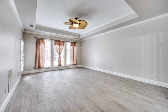 empty room featuring ceiling fan, a raised ceiling, ornamental molding, and light hardwood / wood-style floors