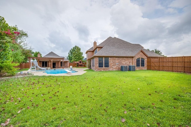 back of property featuring a patio area, a fenced in pool, a yard, and central AC