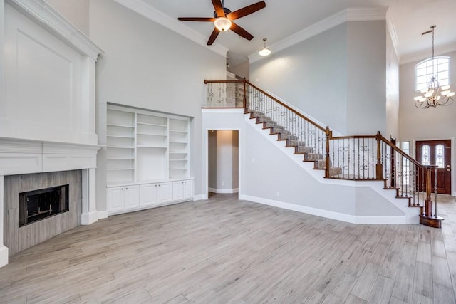 unfurnished living room with a fireplace, light hardwood / wood-style floors, ceiling fan with notable chandelier, and ornamental molding