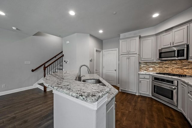 kitchen with stainless steel appliances, sink, dark hardwood / wood-style flooring, and an island with sink