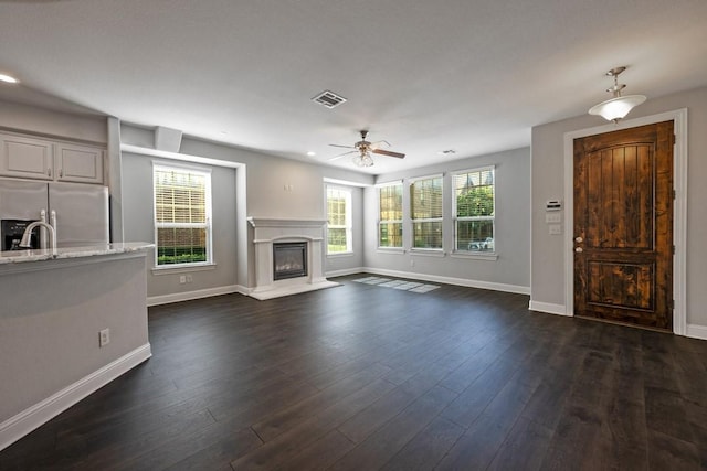 unfurnished living room featuring dark wood-type flooring and ceiling fan