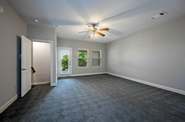 unfurnished room with dark carpet and ceiling fan