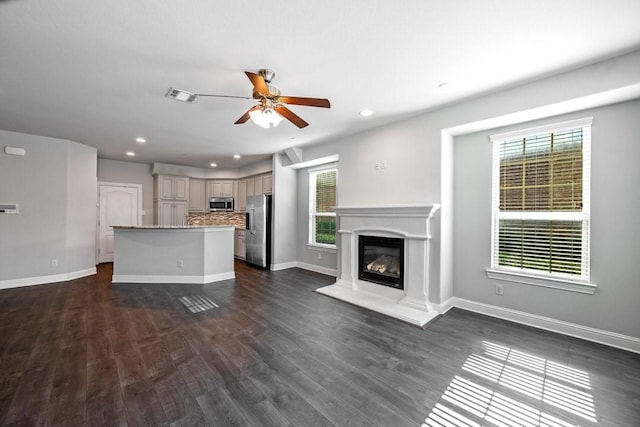 unfurnished living room featuring a wealth of natural light, dark hardwood / wood-style floors, and ceiling fan