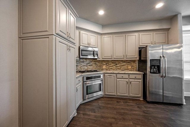 kitchen featuring light stone counters, backsplash, stainless steel appliances, and dark hardwood / wood-style floors