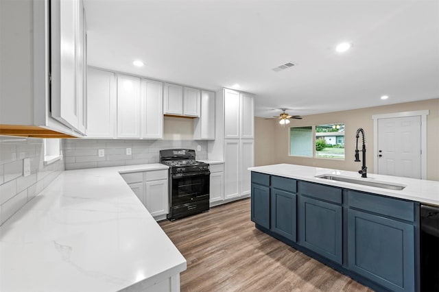 kitchen with backsplash, ceiling fan, light hardwood / wood-style floors, black appliances, and sink