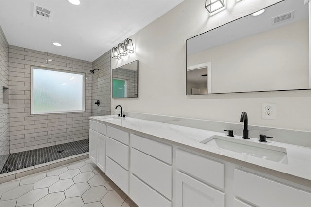 bathroom with tiled shower, tile patterned floors, and dual bowl vanity