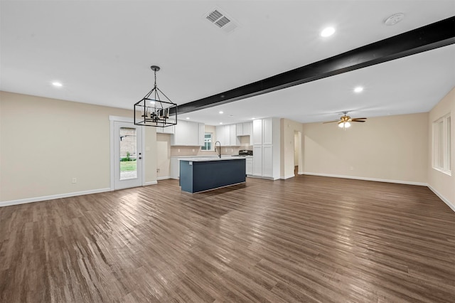 unfurnished living room featuring beamed ceiling, sink, dark hardwood / wood-style flooring, and ceiling fan with notable chandelier