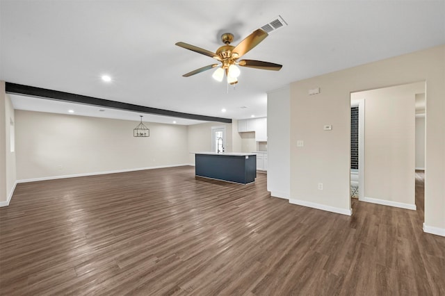 unfurnished living room featuring beam ceiling, dark wood-type flooring, sink, and ceiling fan