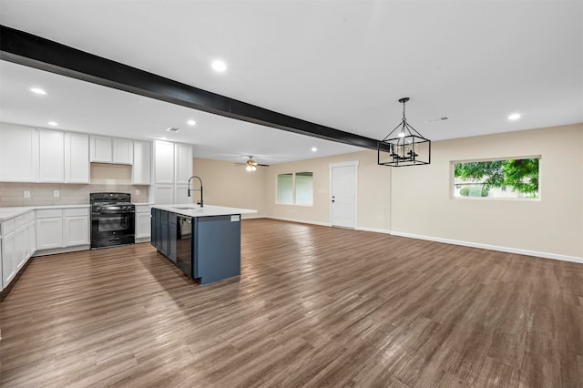 kitchen featuring white cabinetry, black stove, ceiling fan with notable chandelier, hardwood / wood-style floors, and beam ceiling