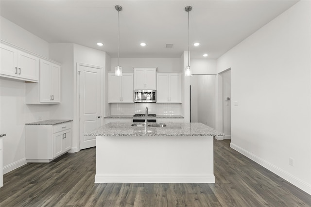 kitchen with dark hardwood / wood-style flooring, white cabinetry, pendant lighting, and a center island with sink