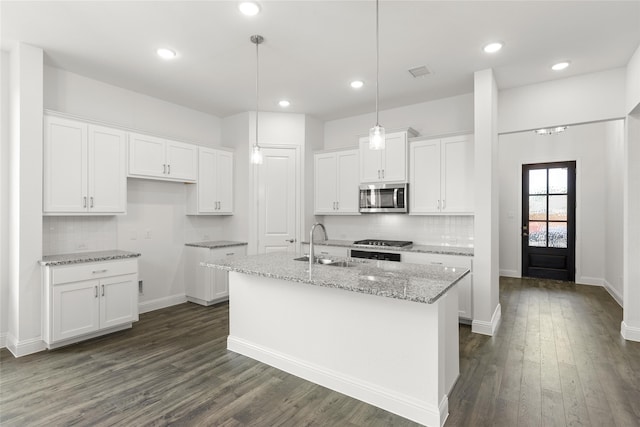 kitchen with white cabinets, stainless steel appliances, dark wood-type flooring, and a center island with sink