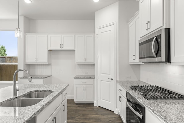 kitchen featuring stainless steel appliances, white cabinets, hanging light fixtures, sink, and dark hardwood / wood-style floors