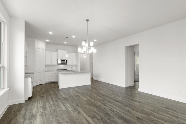 kitchen with white cabinetry, hanging light fixtures, a center island with sink, and dark hardwood / wood-style floors