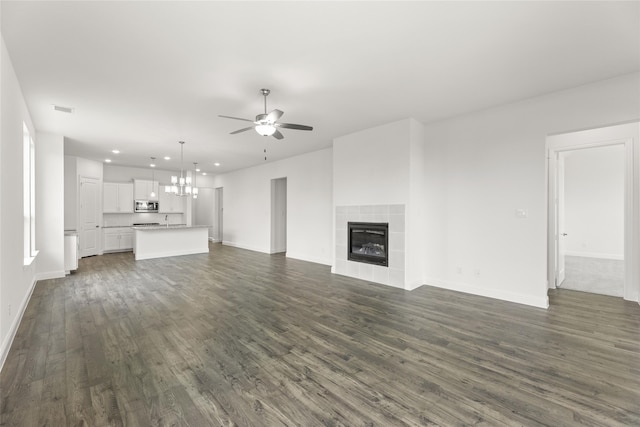 unfurnished living room with dark wood-type flooring, a tiled fireplace, and ceiling fan