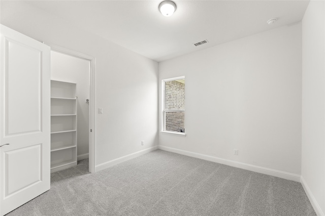 unfurnished bedroom with light carpet, a closet, and a spacious closet