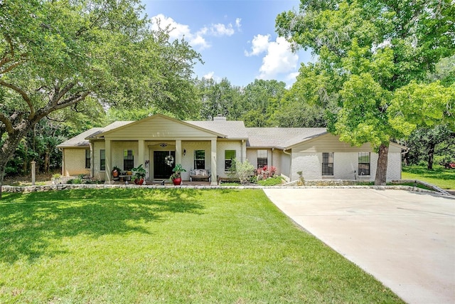 view of front of home with brick siding, a porch, driveway, and a front lawn