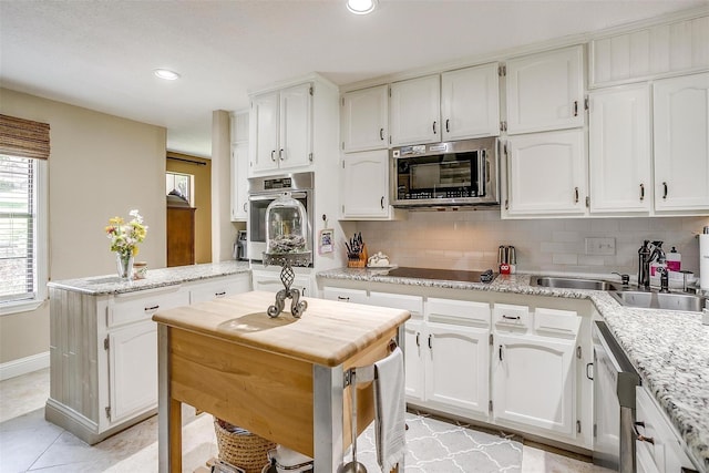 kitchen featuring backsplash, appliances with stainless steel finishes, and white cabinets