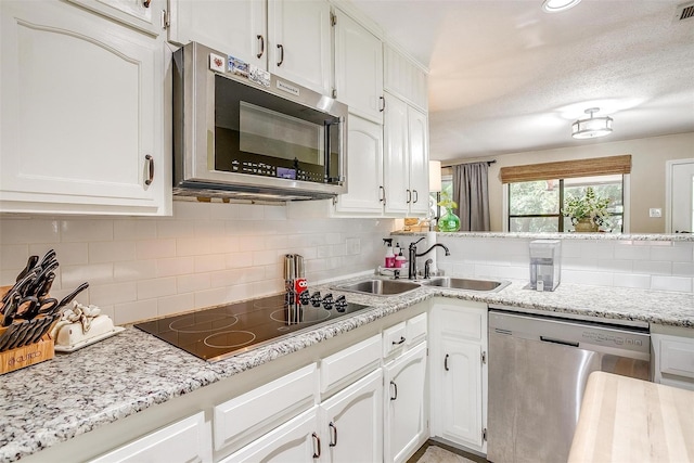 kitchen featuring appliances with stainless steel finishes, white cabinetry, a textured ceiling, and decorative backsplash