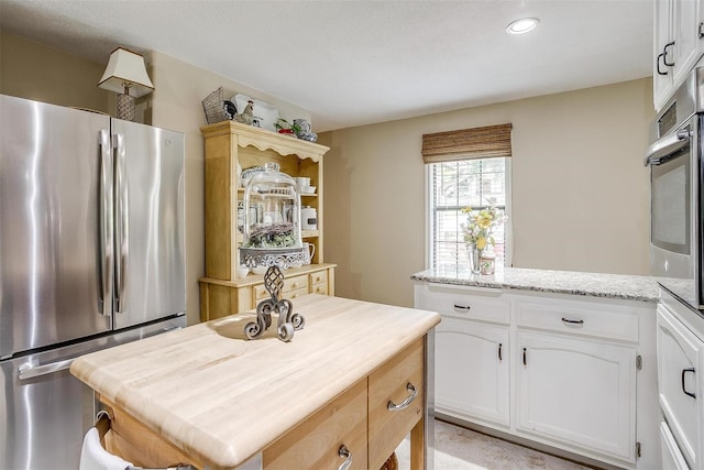 kitchen featuring white cabinets, light stone counters, and stainless steel appliances