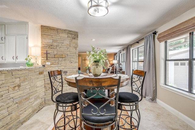 dining space with baseboards, light tile patterned floors, and a textured ceiling