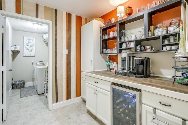 bar featuring white cabinets, light tile patterned floors, a textured ceiling, washer and dryer, and wine cooler