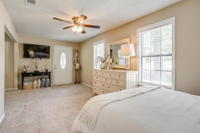 bedroom featuring light carpet, multiple windows, visible vents, and a textured ceiling