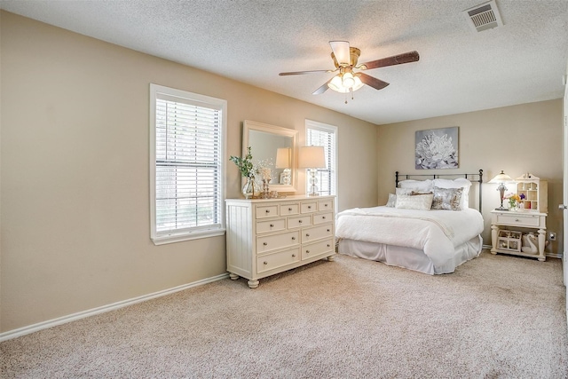 bedroom with baseboards, a textured ceiling, visible vents, and light colored carpet