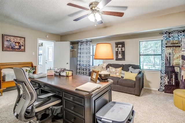 office area with baseboards, a textured ceiling, ceiling fan, and light carpet