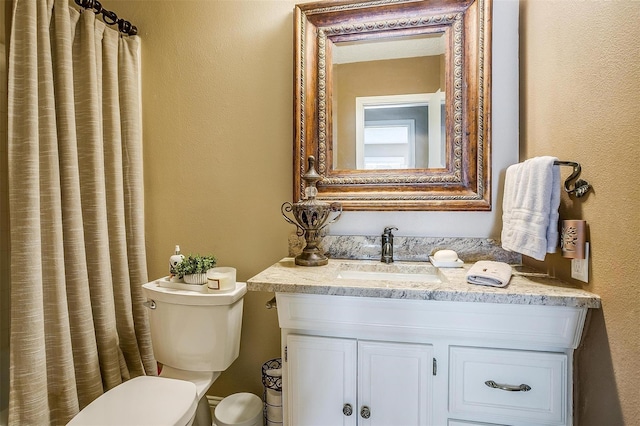 bathroom featuring a textured wall, toilet, and vanity