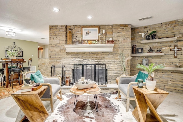 living room featuring recessed lighting, a textured ceiling, a fireplace, and visible vents