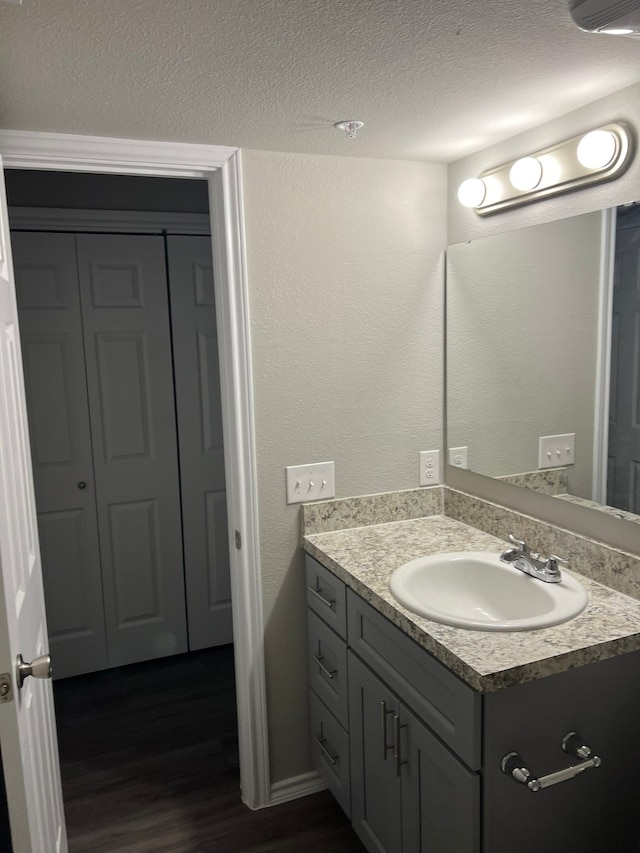 bathroom with wood-type flooring, vanity, and a textured ceiling