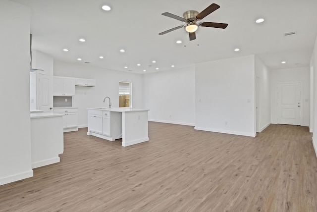 unfurnished living room featuring sink, light hardwood / wood-style flooring, and ceiling fan