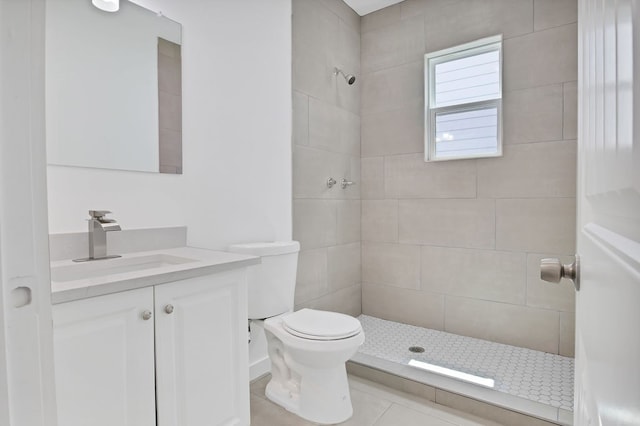 bathroom with vanity, a tile shower, tile patterned flooring, and toilet