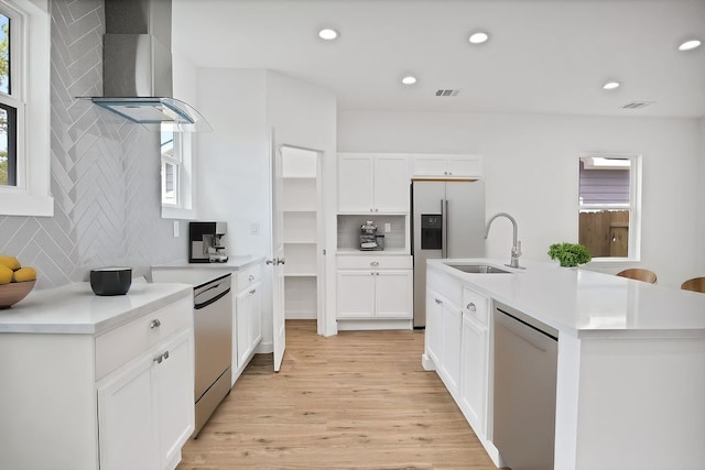 kitchen featuring stainless steel dishwasher, white cabinetry, light hardwood / wood-style flooring, and wall chimney exhaust hood