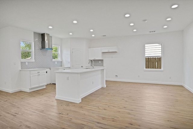 kitchen with white cabinetry, wall chimney exhaust hood, and light wood-type flooring