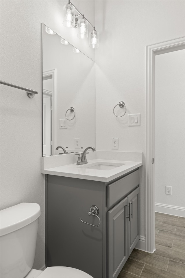 bathroom with hardwood / wood-style flooring, vanity, and toilet