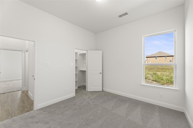 unfurnished bedroom featuring a closet, a spacious closet, and light colored carpet