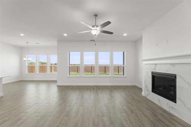 unfurnished living room with a fireplace, hardwood / wood-style flooring, and ceiling fan with notable chandelier