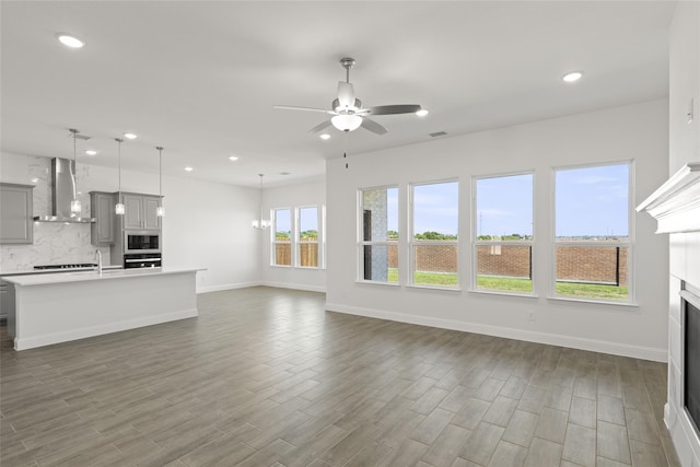 unfurnished living room featuring hardwood / wood-style flooring and ceiling fan with notable chandelier