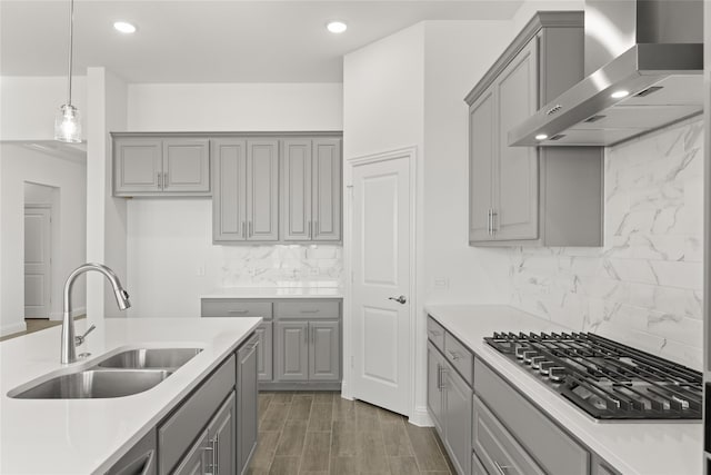 kitchen with gray cabinets, wall chimney exhaust hood, and sink