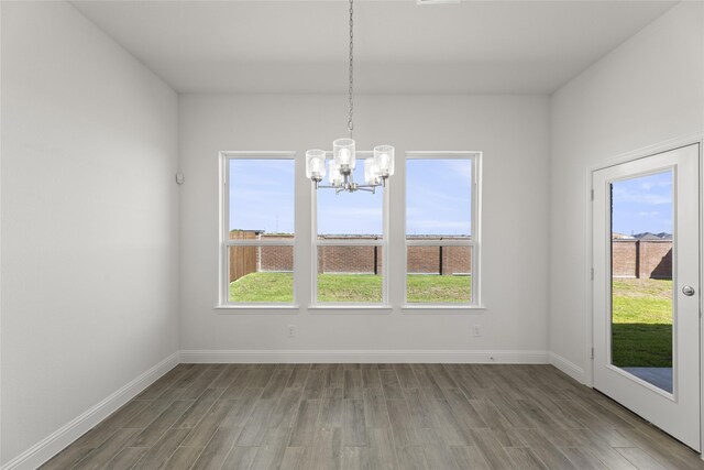 unfurnished dining area featuring hardwood / wood-style flooring and a chandelier