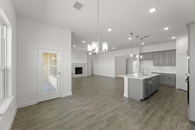 kitchen featuring dishwasher, gray cabinetry, hanging light fixtures, and a center island with sink