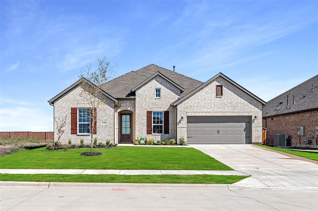 french country home featuring a garage, central air condition unit, and a front yard