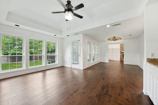 unfurnished living room with ceiling fan, dark hardwood / wood-style floors, and a tray ceiling