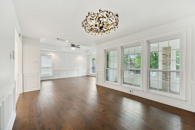 unfurnished living room featuring ceiling fan with notable chandelier and dark hardwood / wood-style floors