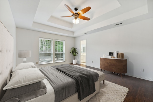 bedroom featuring ceiling fan, wood-type flooring, connected bathroom, and a tray ceiling