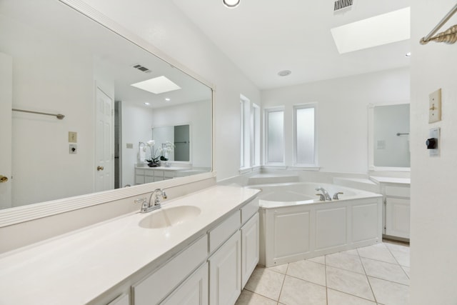 bathroom featuring tile patterned flooring, a tub, a skylight, and vanity