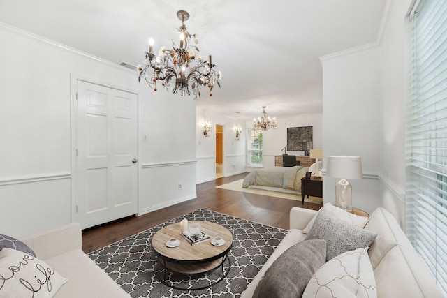 living room featuring dark hardwood / wood-style flooring, ornamental molding, and an inviting chandelier